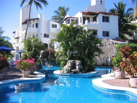 a swimming pool in front of a large building at Hotel Villas Los Angeles in Manzanillo