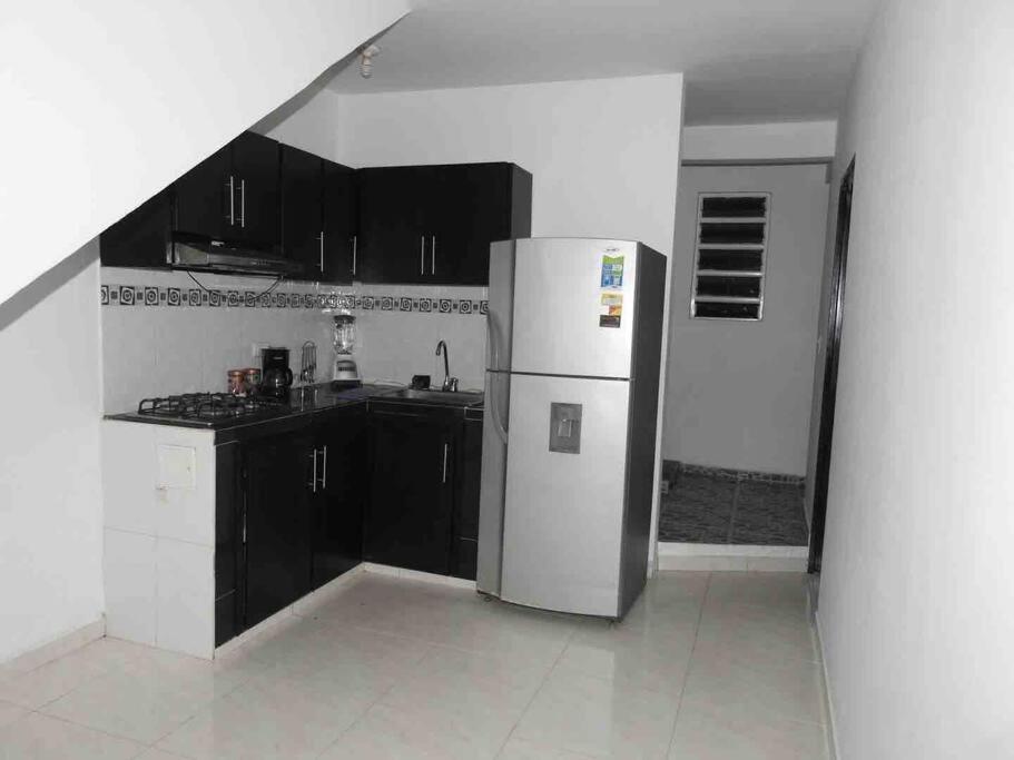 a kitchen with a refrigerator and black cabinets at Apartamento familiar Obdulio in Villavicencio