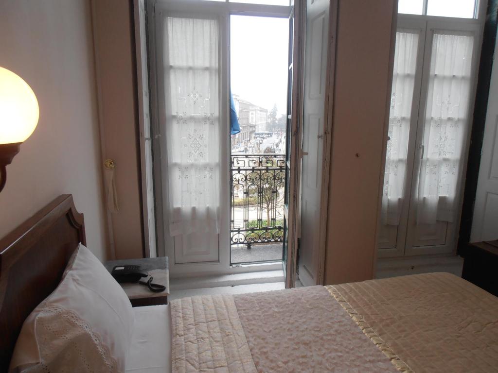 1 dormitorio con 1 cama y puerta con balcón en Hotel S. Marino en Oporto