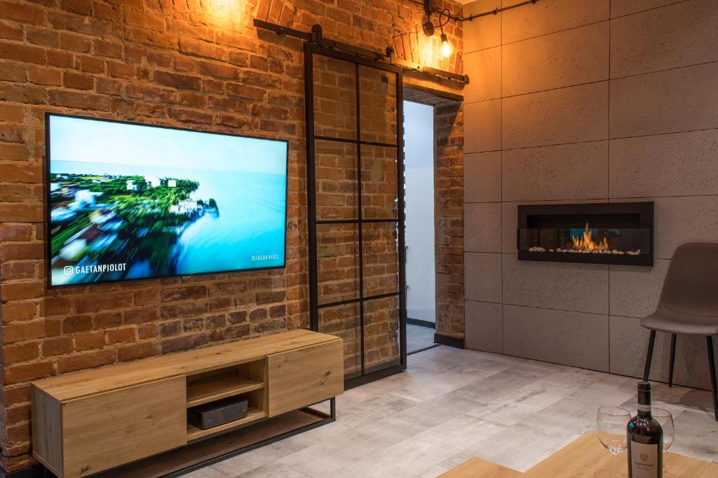 a living room with a television on a brick wall at Apartament Black Loft in Nysa
