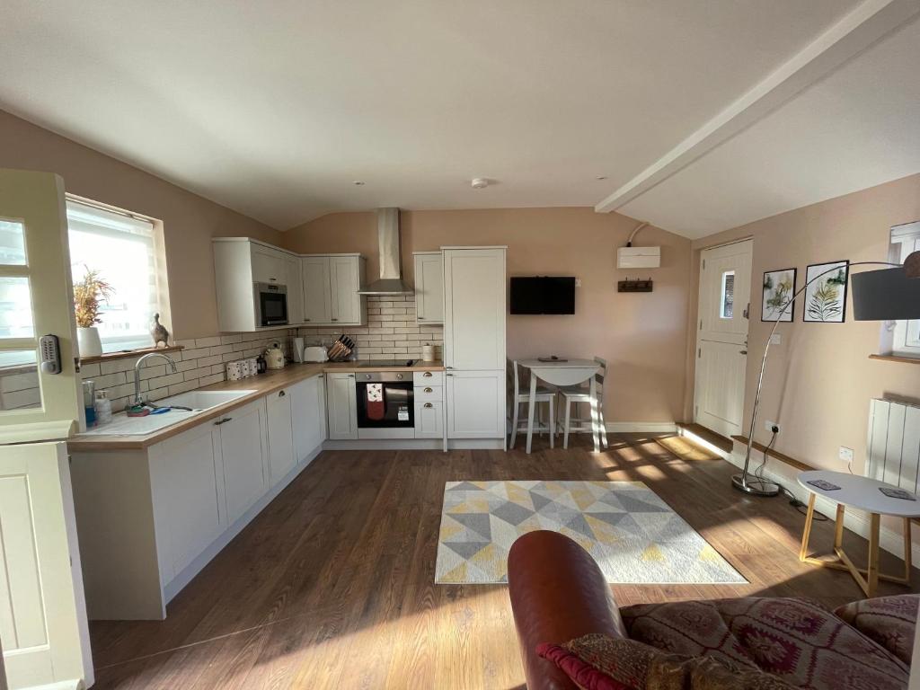 a large kitchen with white cabinets and a table at Beech Cottage in Bodiam