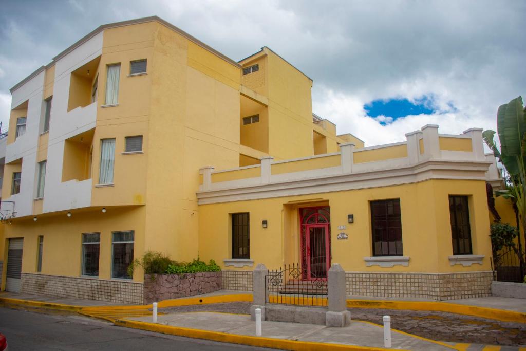 a yellow building with a red door on a street at Hotel Mac Arthur in Tegucigalpa