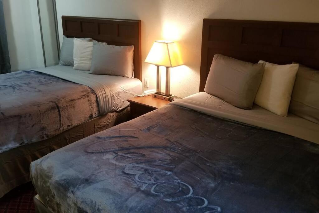 a hotel room with two beds and a lamp at OSU 2 Queen Beds Hotel Room 128 Booking in Stillwater