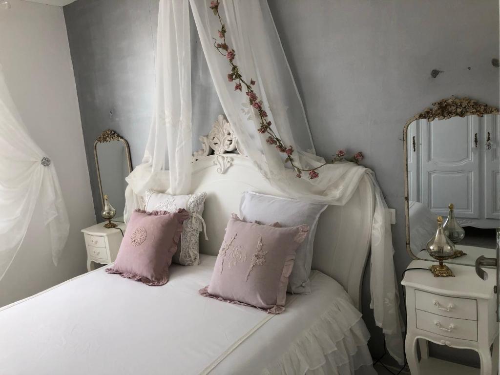 a white bed with pink pillows and a canopy at MAISON CHATEAU D'OLERON in Le Château-dʼOléron
