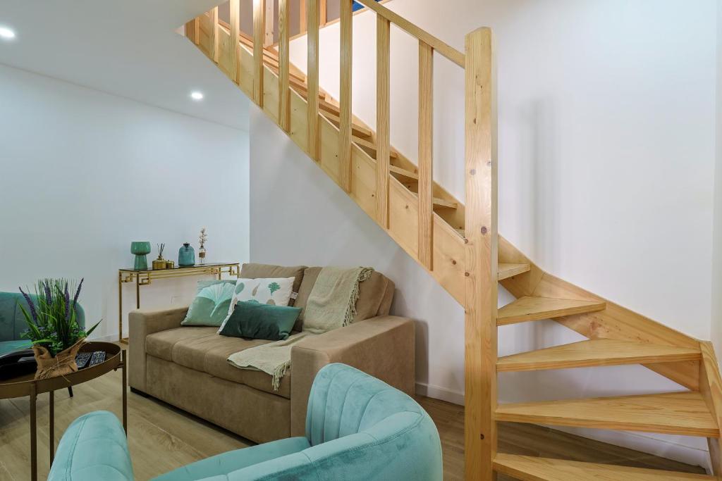 a living room with a couch and a wooden staircase at Casa do Arco in Ponta Delgada