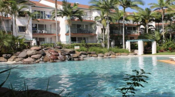 a swimming pool in front of a building with palm trees at Grande Florida - Hosted by Burleigh Letting in Gold Coast