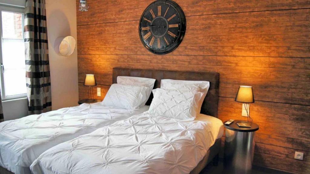 una camera da letto con un letto con un orologio sul muro di Les Béthunoises Centre Grand-Place - Spa et Sauna a Béthune