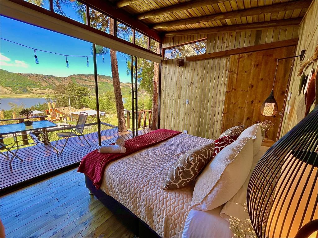 a bedroom with a bed and a balcony with a table at Alma de Campo Glamping - Laguna de Suesca in Suesca