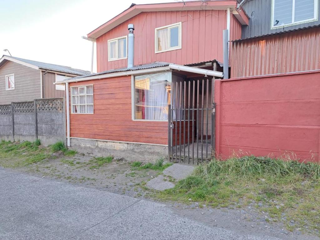 uma casa vermelha com uma cerca em frente em Cabaña Alba em Puerto Montt