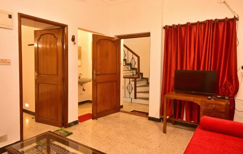 a living room with a tv and a red curtain at Villa Felicia in Puducherry