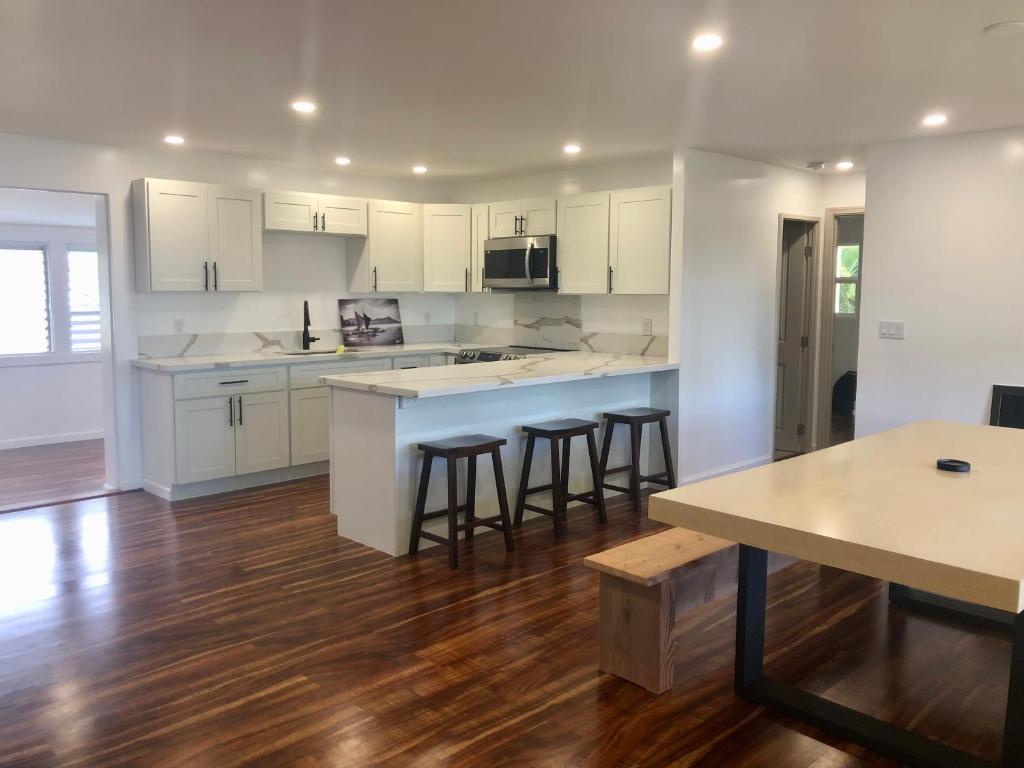 an open kitchen with white cabinets and bar stools at Mākaha House in Waianae