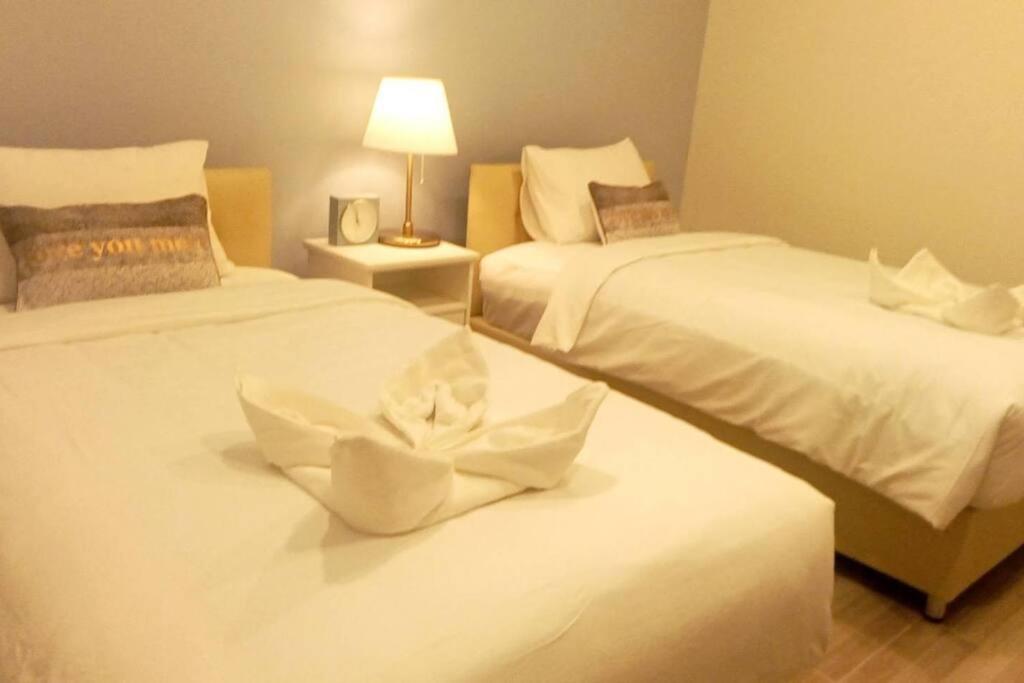 una camera con 2 letti con lenzuola bianche e una lampada di Na - cha - lae (3) a Chanthaburi