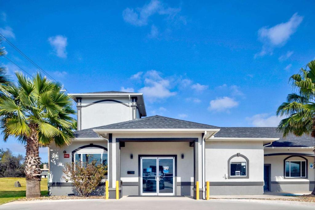 a white house with palm trees in front of it at Studio 6-Pleasanton, TX in Pleasanton