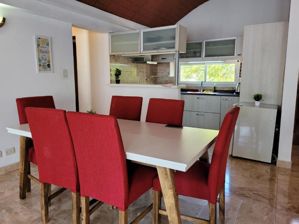 cocina con mesa blanca y sillas rojas en Sherman en Tigre