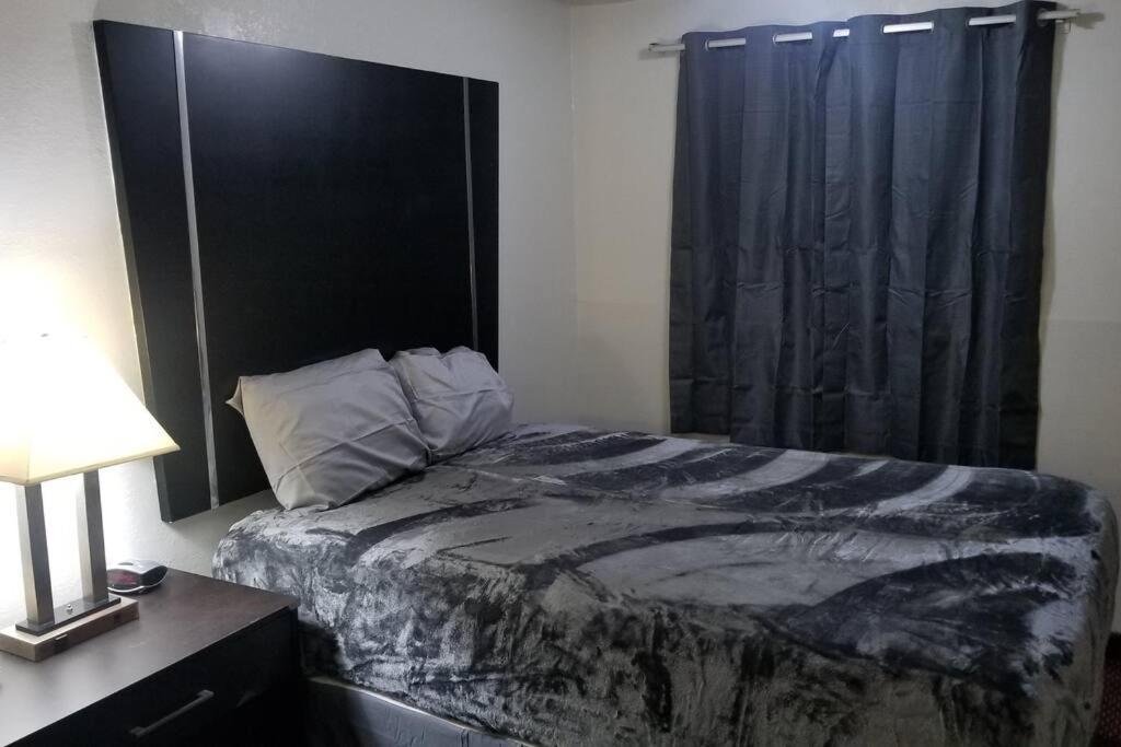 a bedroom with a bed with a black headboard and a window at OSU 2 Queen Beds Hotel Room 131 Wi-Fi Hot Tub Booking in Stillwater
