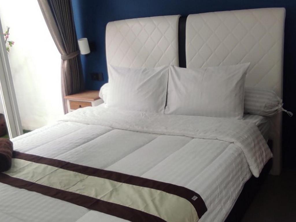 uma grande cama branca com lençóis e almofadas brancos em Aliandra Villa by The Lavana em Yogyakarta