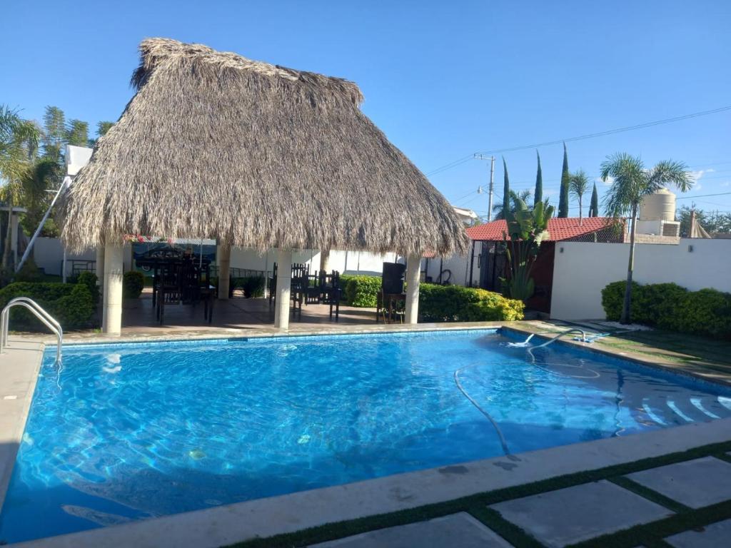 une grande piscine avec un toit de chaume et une piscine dans l'établissement QUINTA GARCIA HUIJON, 