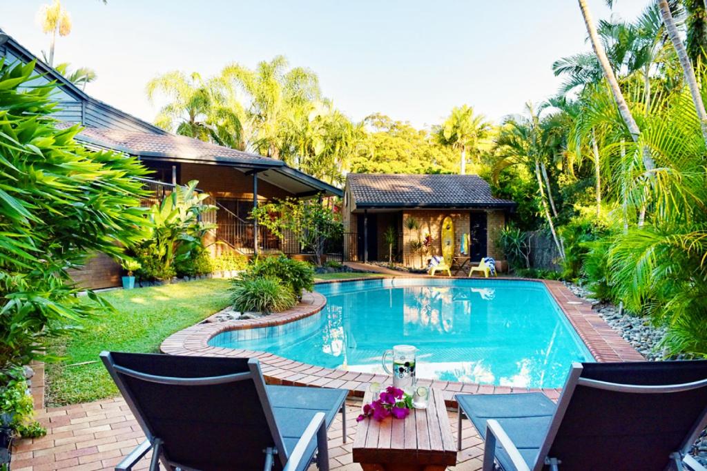 een villa met een zwembad en een huis bij Diggers Beach Surf House in Coffs Harbour
