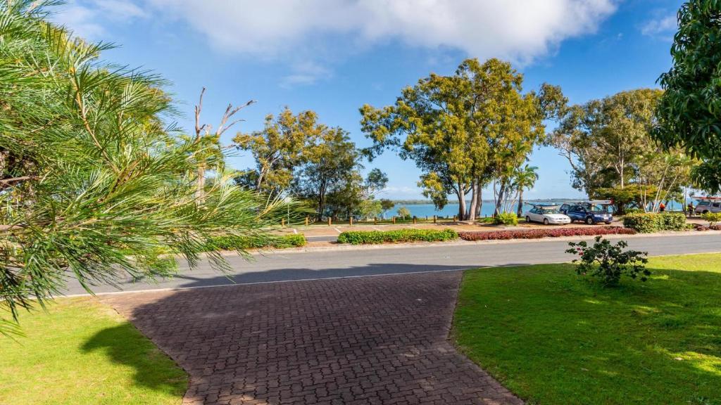 a street in a park with trees and a road at Bribie Beach House, Waterfront directly across the road - Solander Esp, Banksia Beach in Old Bribie