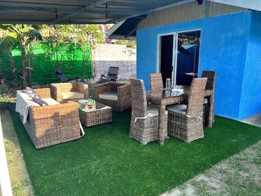 Fare Ninamu Maison individuel 2 chambres في بورا بورا: مجموعة من الكراسي الخوص والطاولات على العشب