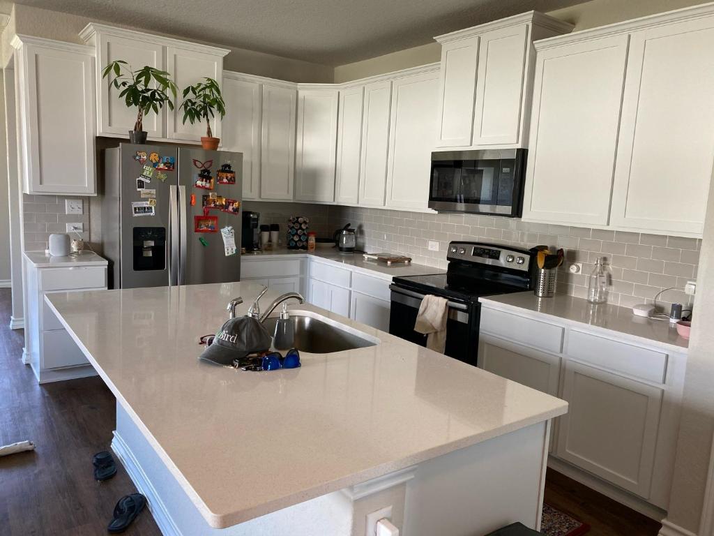 een keuken met witte kasten en een roestvrijstalen koelkast bij New home less than 5 minutes from Lackland Base private room in San Antonio