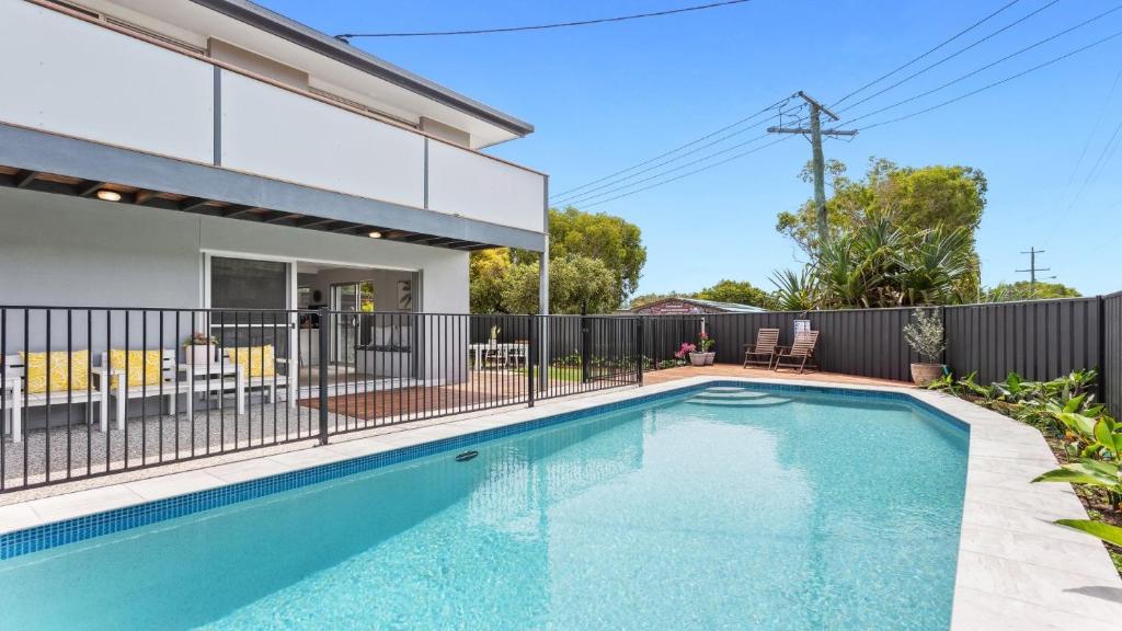 a swimming pool in front of a house with a fence at 1 Ilya Street Currimundi QLD in Kawana Waters