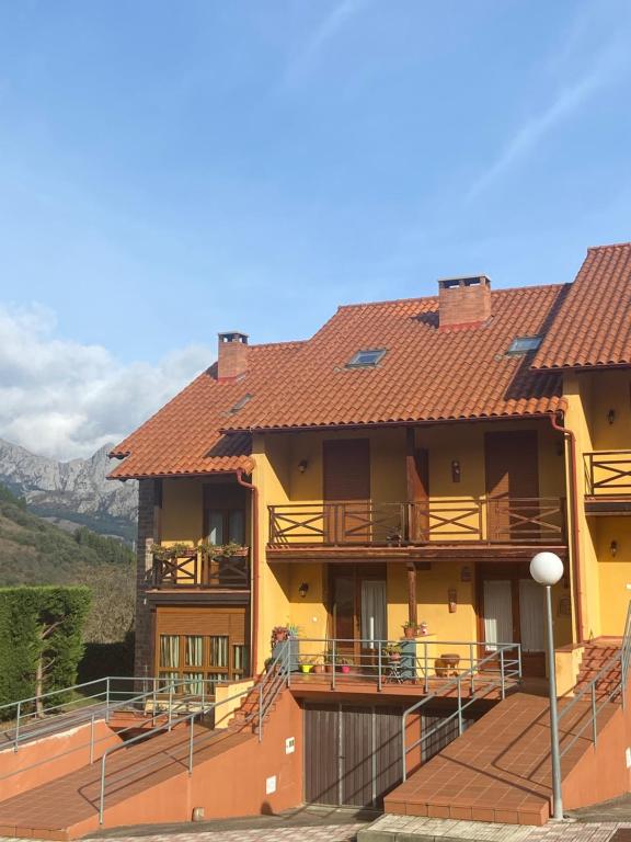 een geel gebouw met een terras en bergen op de achtergrond bij El RINCÓN DE OJEDO -POTES- PICOS DE EUROPA- in Ojedo