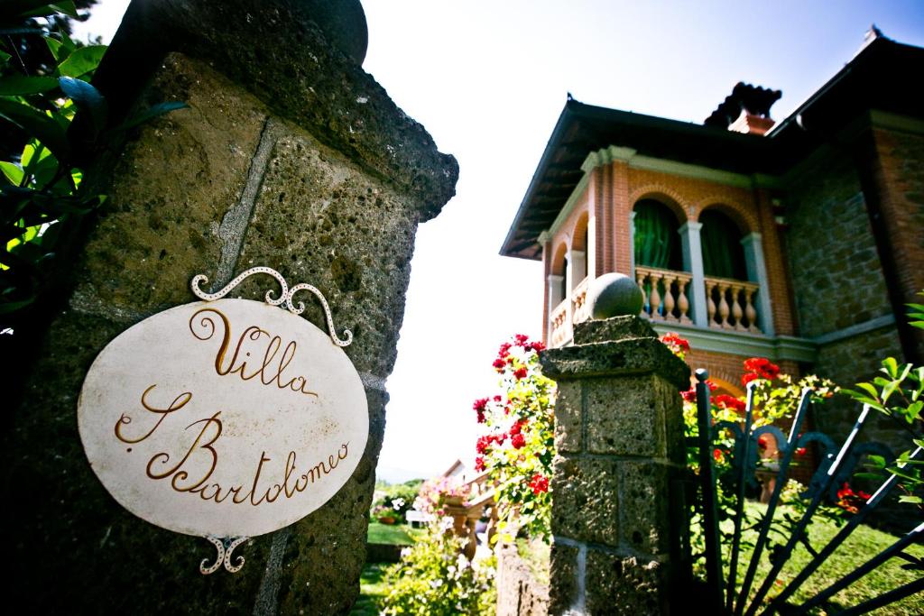 um sinal numa cerca de pedra em frente a uma casa em San Bartolomeo Suite em Castel Rigone