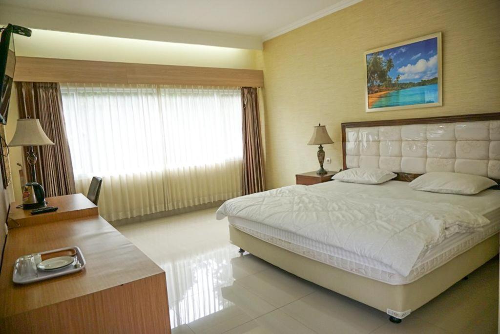 a bedroom with a large bed and a large window at Griya Kayana Inn and Villas in Bogor
