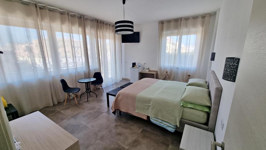 Schlafzimmer mit einem Bett, einem Tisch und Stühlen in der Unterkunft MERIDIAN B&B in Syrakus