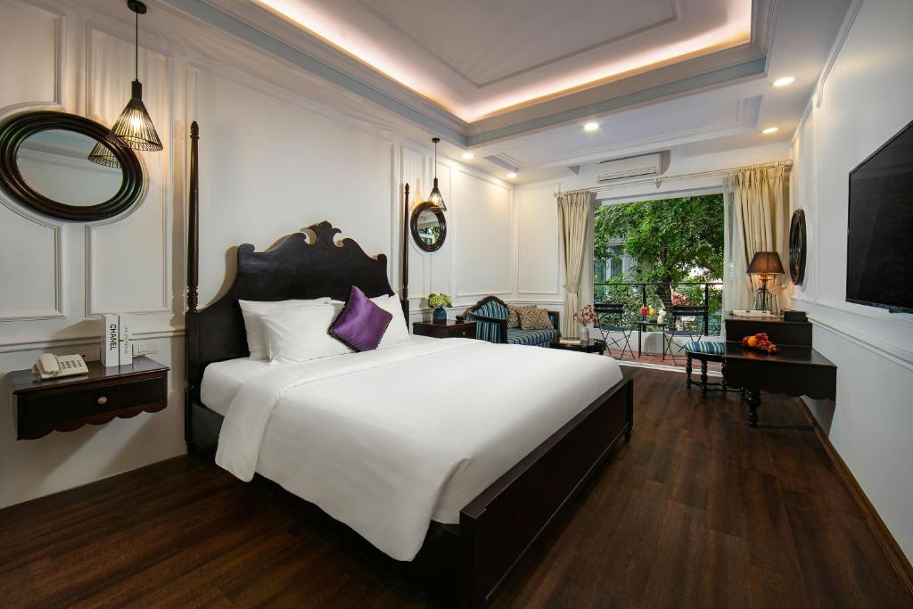 a bedroom with a large white bed with a purple pillow at San Boutique Hotel in Hanoi