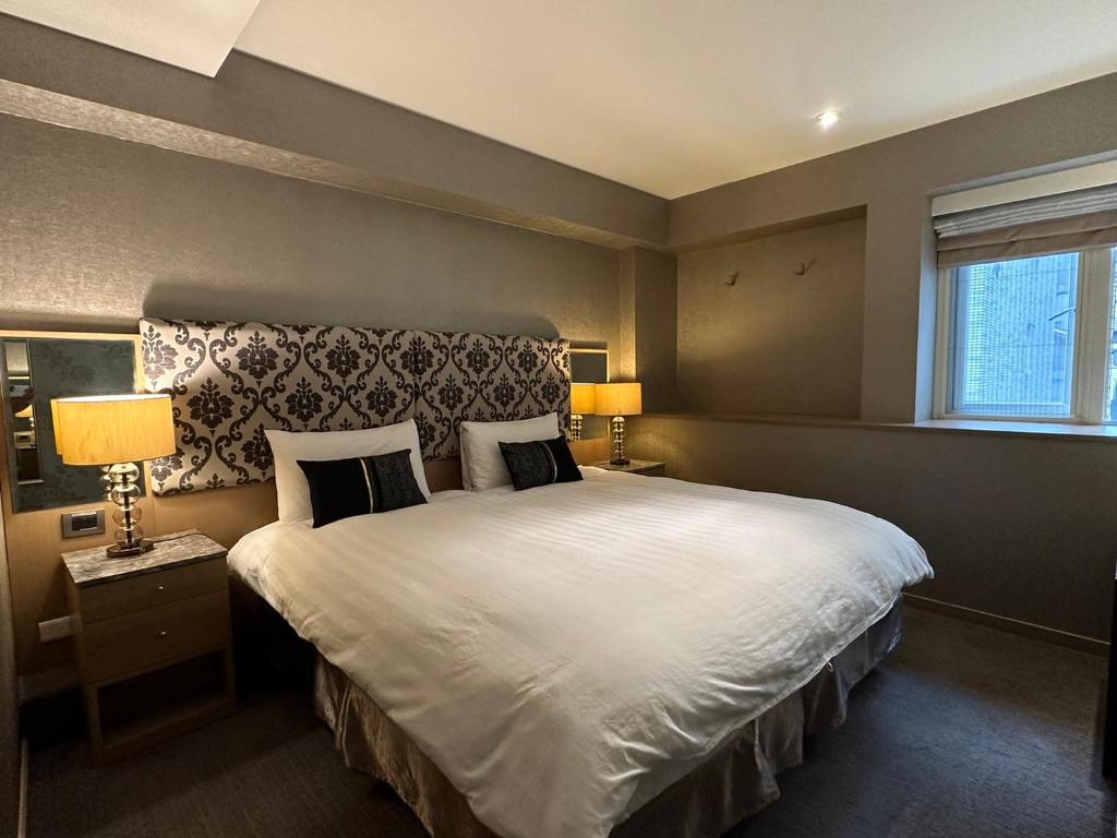 ein Schlafzimmer mit einem großen weißen Bett mit zwei Lampen in der Unterkunft 銀座飯店Ginza Hotel in Taipeh