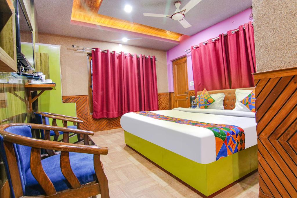 a bedroom with a large bed and red curtains at Hotel City Plaza in Dharamshala