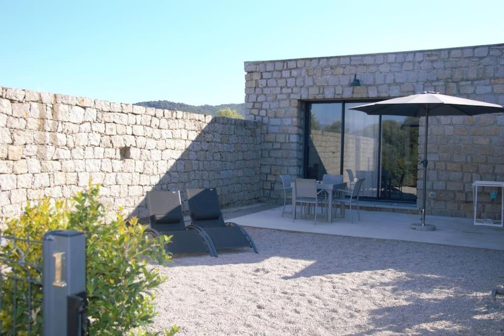 une terrasse avec un parasol, des chaises et une table dans l'établissement N°1 - Maison T2, à Ajaccio