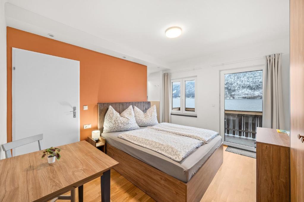 1 dormitorio con 1 cama, escritorio y ventanas en Hallstatt Lakeside Top 4 - Zimmer mit Balkon en Hallstatt