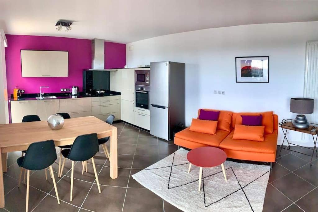 sala de estar con sofá naranja y mesa en APPARTEMENT PLAGE EN RESIDENCE ENTIER 2 CHAMBRES, en Capbreton