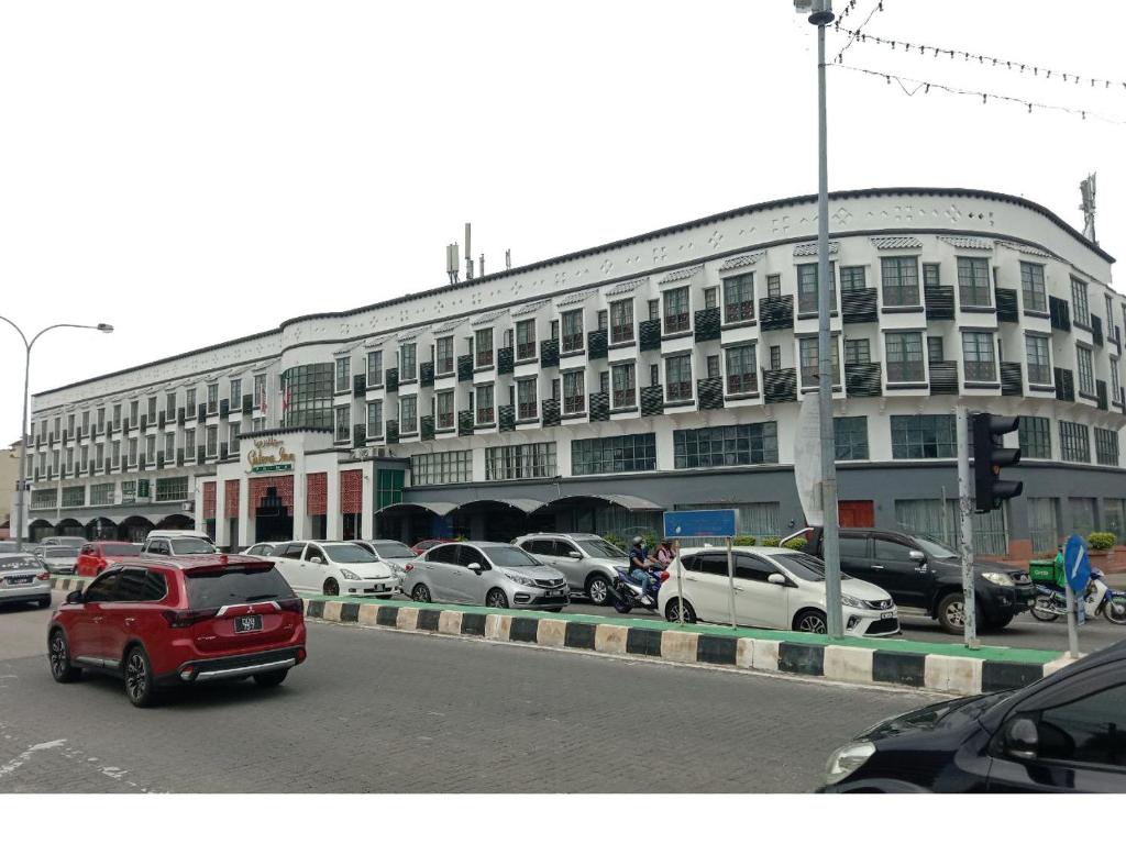 a large building with cars parked in a parking lot at Sutera Inn Prima Hotel in Kota Bharu