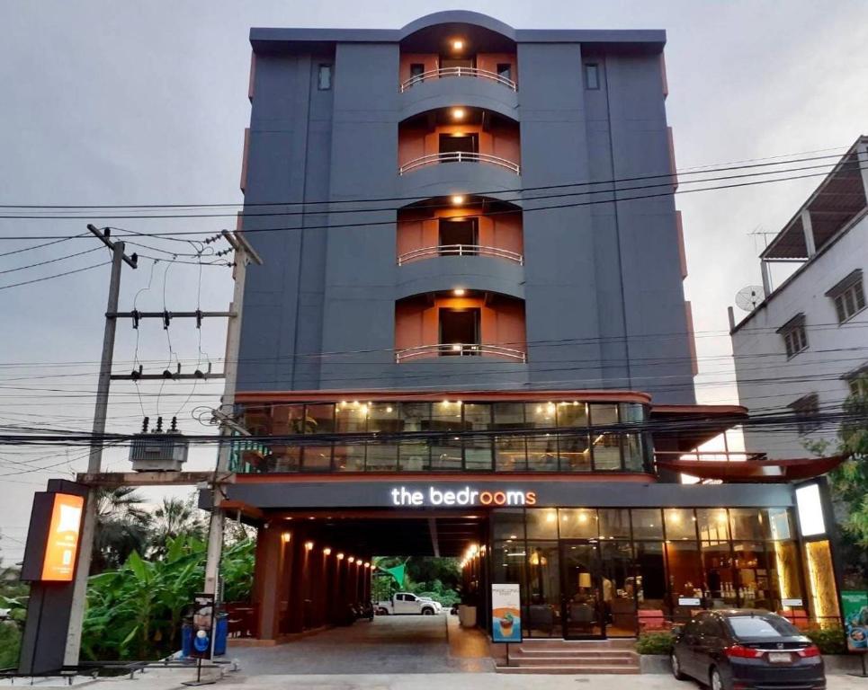 un grand bâtiment avec un panneau devant lui dans l'établissement The Bedrooms Maeklong and Services Apartment, à Samut Songkhram