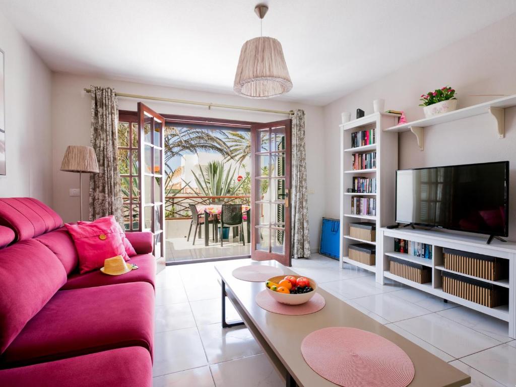 a living room with a pink couch and a table at 10A Amarilla Bay Pool Smart TV WI FI in Costa Del Silencio
