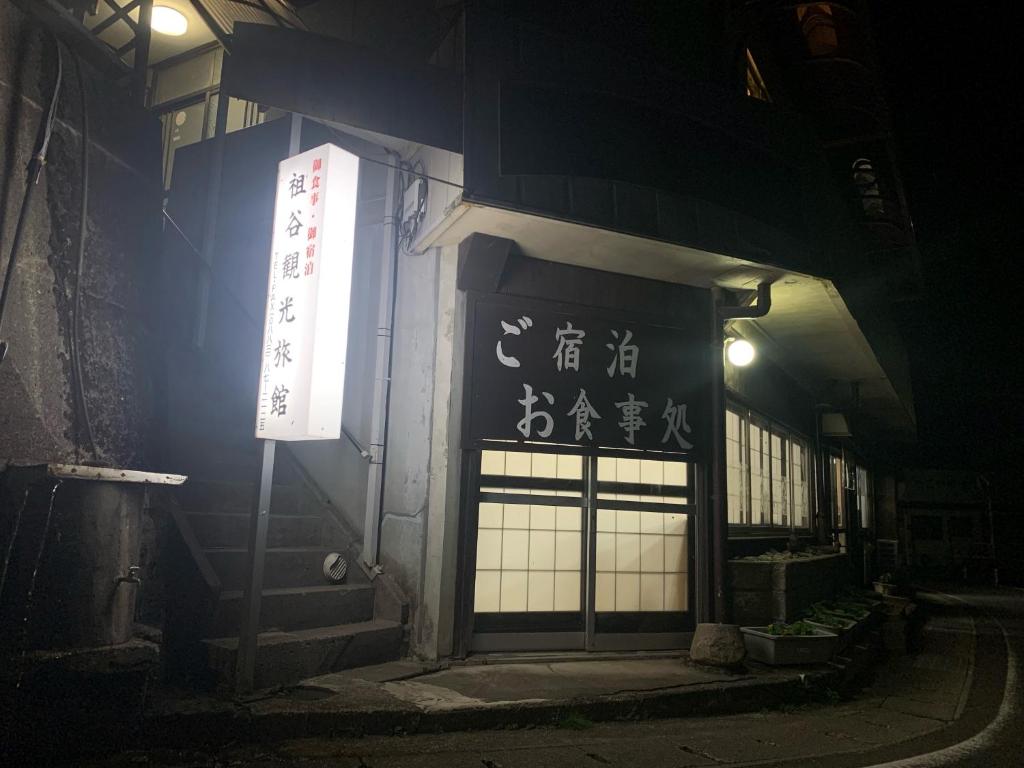 um edifício com uma placa ao lado à noite em Iya Kankou Ryokan em Miyoshi