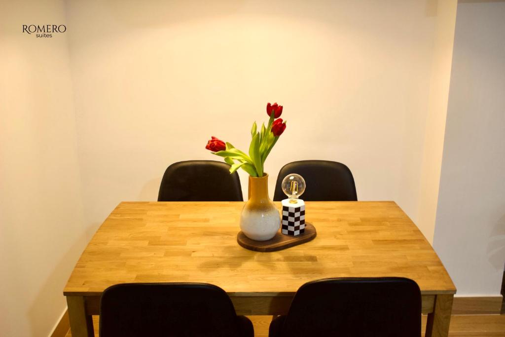 Romero Suites 1 في قرطبة: طاولة مع مزهرية مع زهور الأقحوان الحمراء فيها