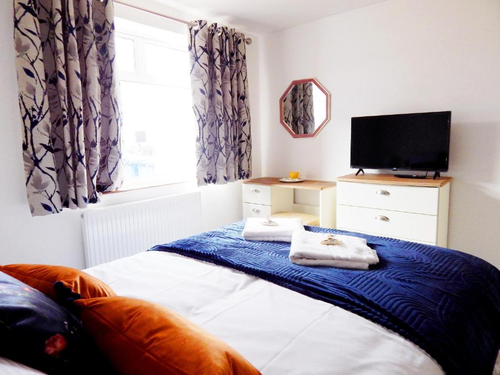 a bedroom with a bed and a flat screen tv at Modern, well located en-suite rooms with parking and all facilities in Cambridge
