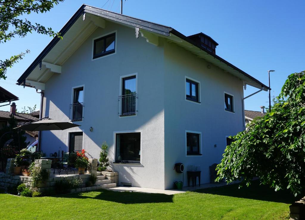 una casa blanca con un patio verde en Ferienwohnung Jenbachtal, en Bad Feilnbach