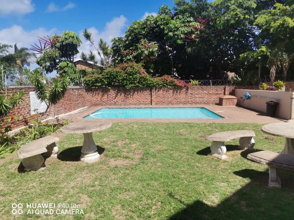 a backyard with two stone benches and a swimming pool at Uvongo Sea Scapes Holiday Apartment in Margate