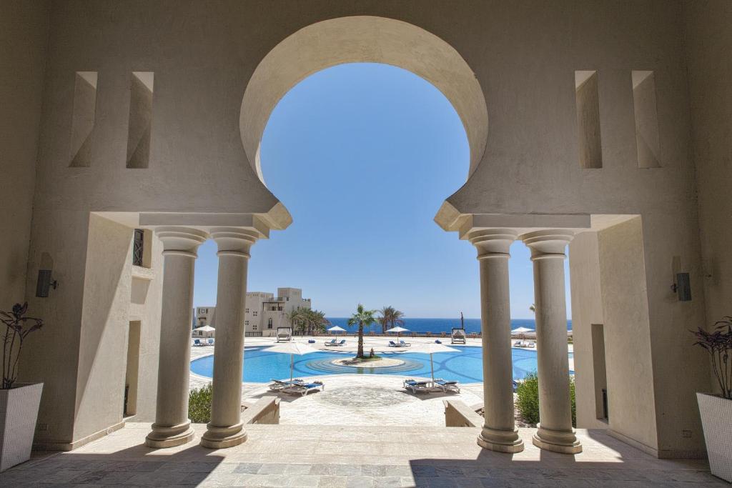 uma vista para uma piscina através de um arco em Azzurra Sahl Hasheesh em Hurghada