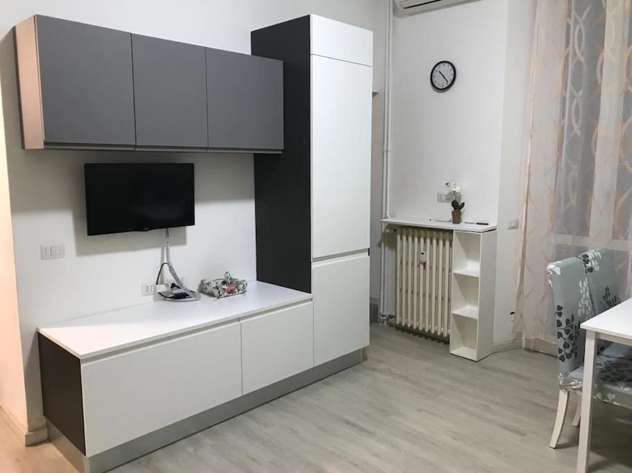 a kitchen with white cabinets and a flat screen tv at Appartamento in zona Bocconi in Milan