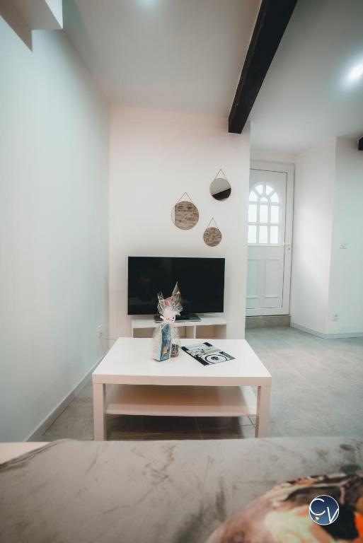 a white living room with a table and a tv at Appartement neuf et moderne dans le centre ville in Bagnols-sur-Cèze