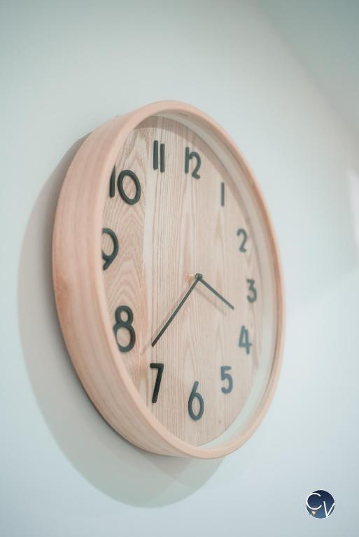 a wooden clock hanging on a white wall at Appartement neuf et moderne dans le centre ville in Bagnols-sur-Cèze
