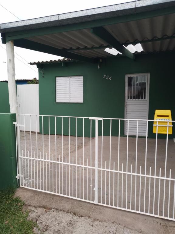 una cerca blanca frente a una casa verde en Kitnet Pousada da T, en Pelotas