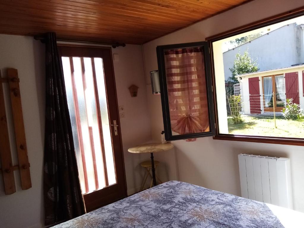 una camera da letto con due grandi finestre e un letto in una stanza di Sous les mimosas a Saint-Jean-de-Monts